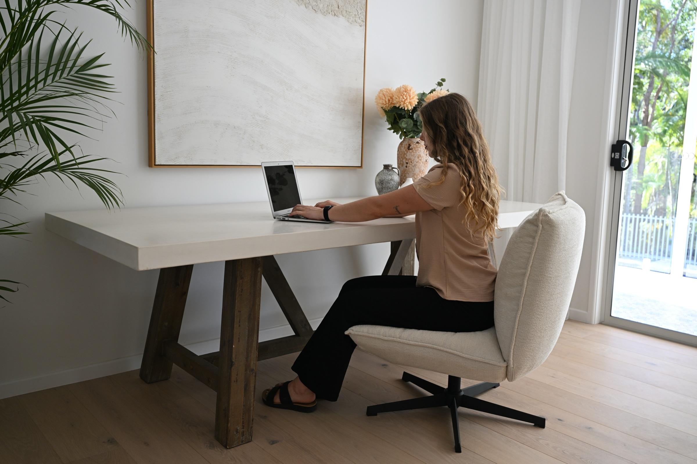 A family assistant working at a laptop at a desk in a bright, calm living room