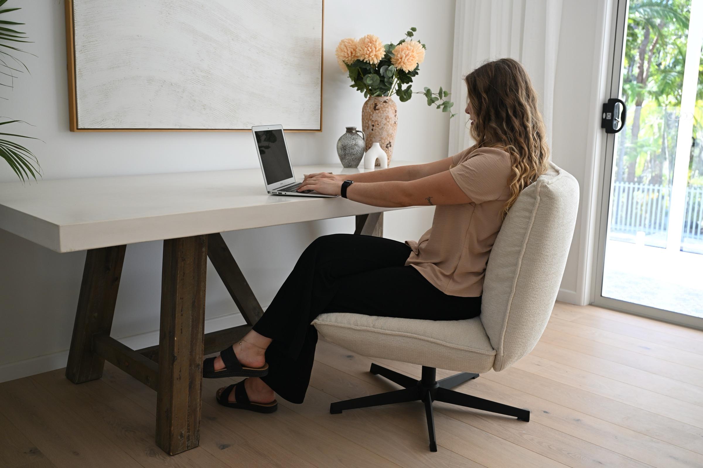 A carer working at a laptop at a white desk in a sunlit room